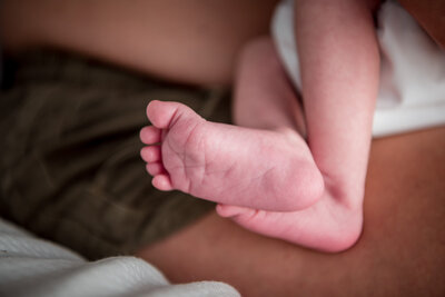 Close-up of newborn foot resting gently on a parent’s lap after birth