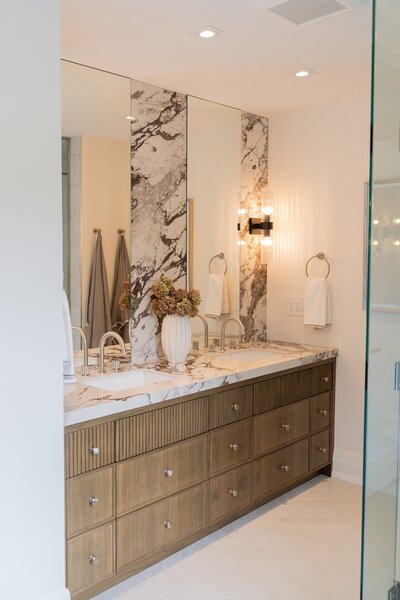 Renovated bathroom with marble walls and wooden cabinets