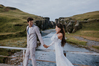 Bride and groom hold hands on a rustic bridge in Iceland’s highlands, perfectly captured by an Iceland wedding photographer.