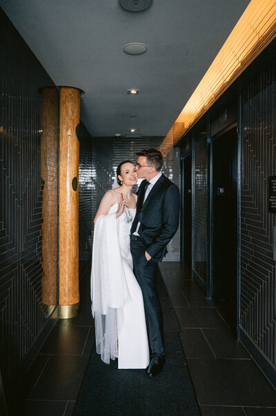 bride and groom kissing in modern hallway