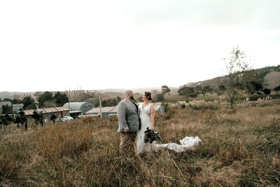 Bride and groom Nardus and Dehlia standing together on grassy hilltop with scenic view, photographed by Zanthe Vorsatz.