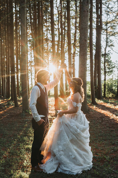 A beautiful bride holding an oversized bridal bouquet with white flowers, standing next to her new husband at wheatfield estate.