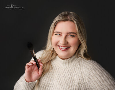 makeup artist smiling and holding makeup brush