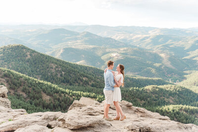 denver wedding photographer with couple holding each other looking at each other and smiling with the woman wearing a white  dress in the mountains
