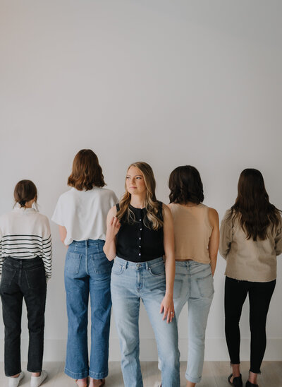 Megan standing and smiling at the camera while her team members stand next to her facing the wall