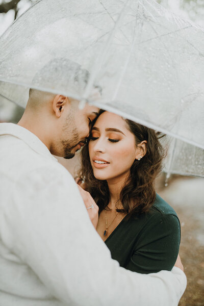 Couple cuddling under an umbrella