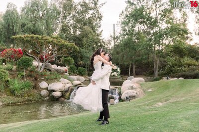 Groom to be lifts his fiance in his arms as they kiss on Table Rock Beach