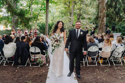 Bride and groom standing amongst plants at New York wedding