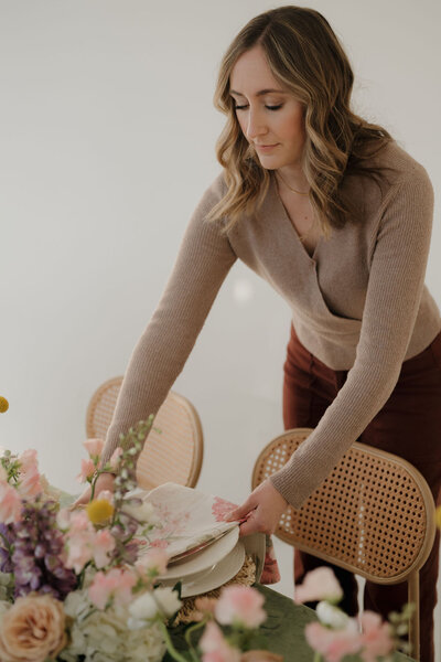 milwaukee event planners, Molly, arranges final details on a wedding table design while smiling.