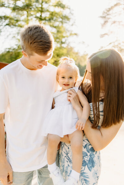mom and dad holding baby in outdoor family photos