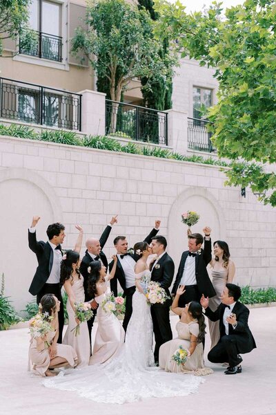 Bride and groom kissing surrounded by cheering bridal party, fun destination wedding captured by Toronto-based photographer