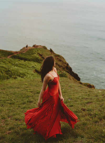 Nature-Spring-Senior-Pictures-in-Oregon-girl-in-red-dress-on-cliffside
