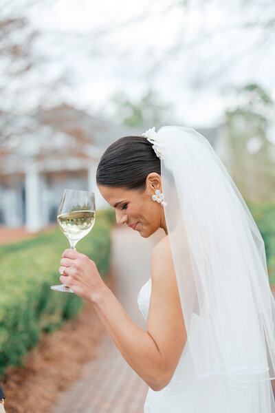bride smiles looking down after sipping white wine at Athens Country Club 