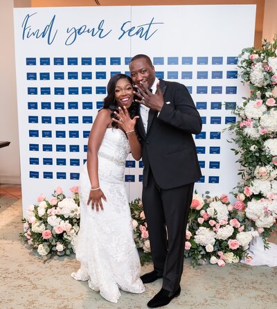 Couple standing together in front of seating chart, Unique Melody Events & Design helped with wedding