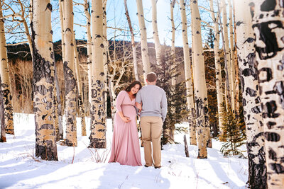 Couple among the aspen trees in the snow for Maternity photos