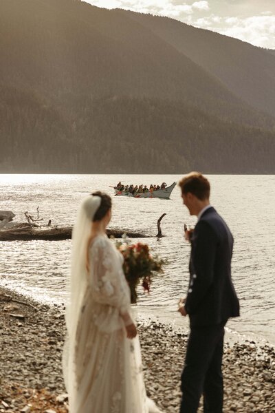 Newlyweds wave to a row boat full of passengers during their romantic Lake Crescent elopement