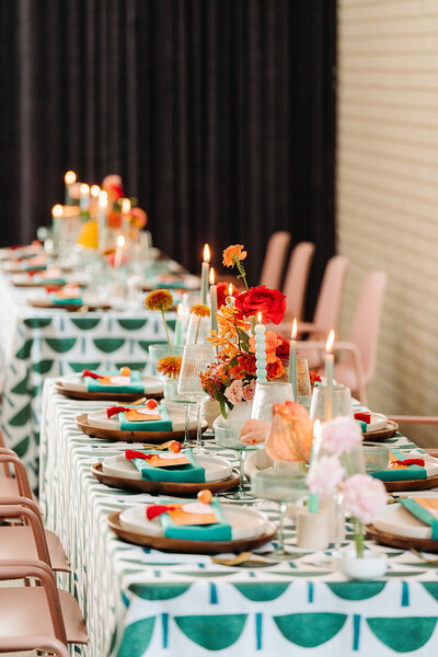 Bold modern wedding tablescape with graphic patterned linens, colorful florals, taper candles, and eclectic place settings styled by Eventive Designs.
