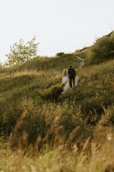 A bride and groom walking along a bluff overlooking lake Michigan near Traverse City.
