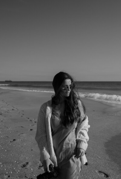 black and white image of girl at the beach looking out to the ocean