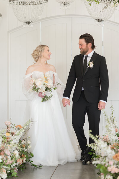 couple holding hands looking at each other walking down the aisle