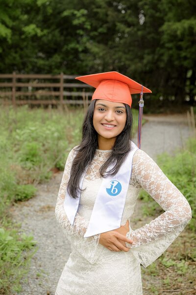 marvin high school graduate dressed in her white dress with her cap and  IB program sash
