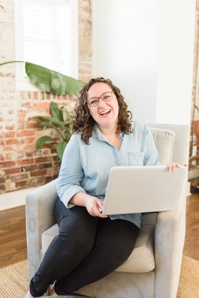 Nashville brand photographer and online marketer posing at an Airbnb with a laptop in her lap