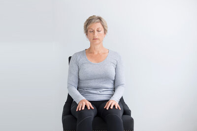 Women in a chair meditating with eyes closed