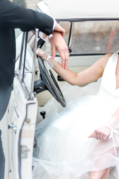detail shot of a bride behind the wheel of a  white car