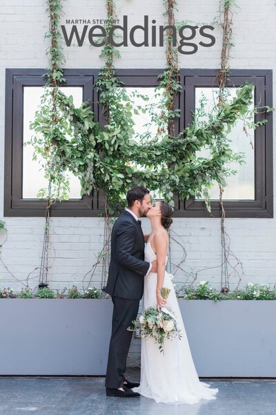 Bride holds her bouquet to her side while being kissed by her groom