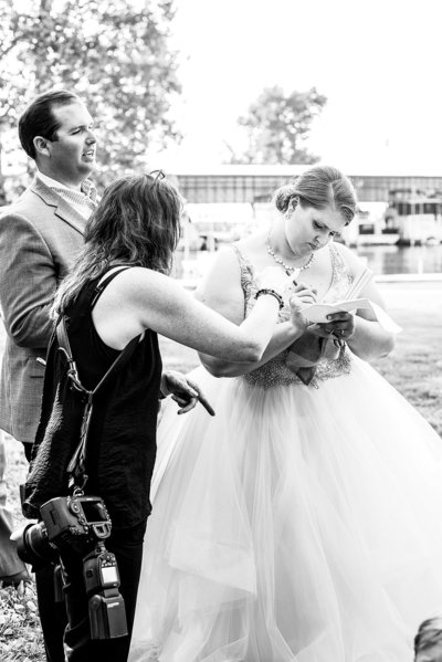 Black and White behind the scenes photo of a photographer helping the bride with her timeline on the wedding day