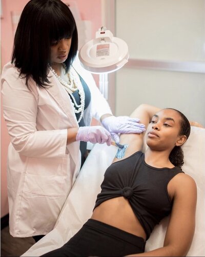 black esthetician waxing armpits of black female client
