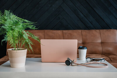 Flat lay of branding session props including laptop, notebook, and coffee on workspace desk.