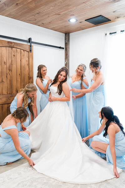 Bride and bridesmaids posing in front of The Grove with rustic barn in background.