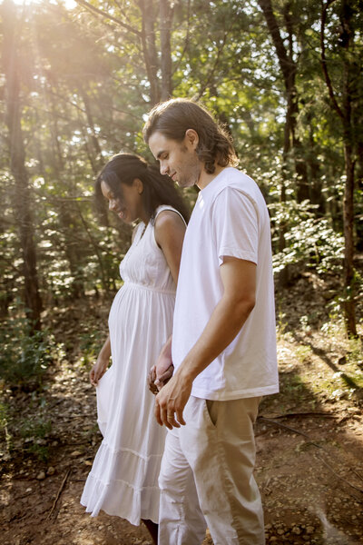 married couple walking in the woods in grapevine texas at a maternity photo session