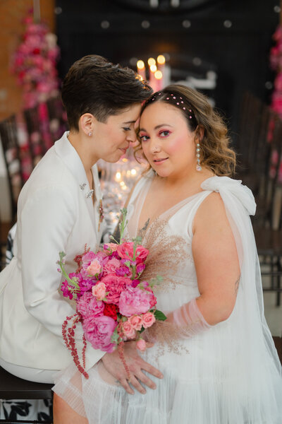 One bride leaning into other bride who is smiling at camera
