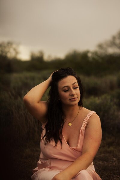 Woman in pink dress, desert backdrop. Moody ambiance.