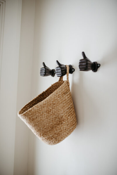 A woven basket hanging on hooks, representing a simple, sustainable approach to home organization and eco-friendly living.