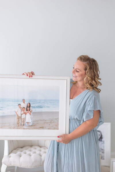 full service family photographer holding framed family portrait from virginia beach family photos