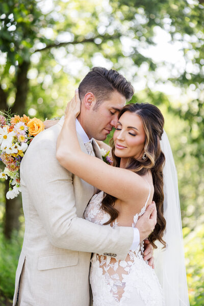 A bride and groom embrace, showing off their new wedding bands