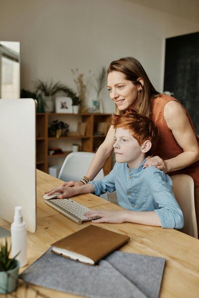 mom helping son at computer with homework