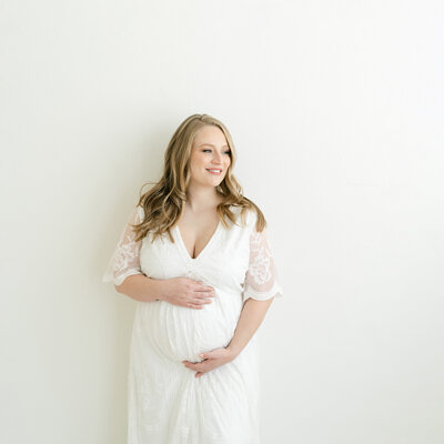 Pregnant mother wearing white ivory dress for maternity photos at Julie Brock Photography in Louisville KY