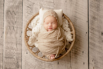 newborn baby boy in a white swaddle laying in an antique crate