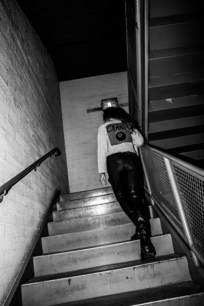 Black and white photo of a blonde woman, Heather Jiron, walking up a flight of stairs