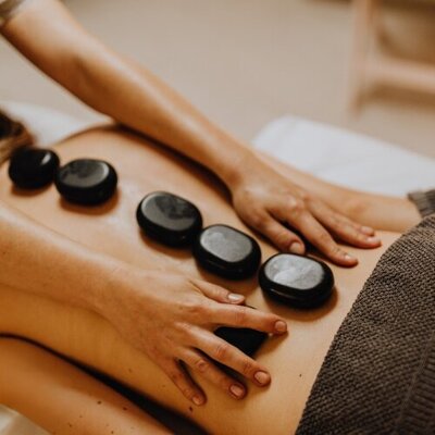 Massage Therapist performing a hat stone massage on the back of client