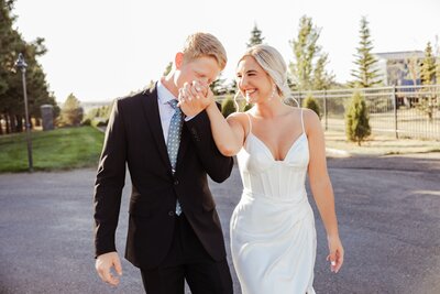 groom kissing brides hand while walking