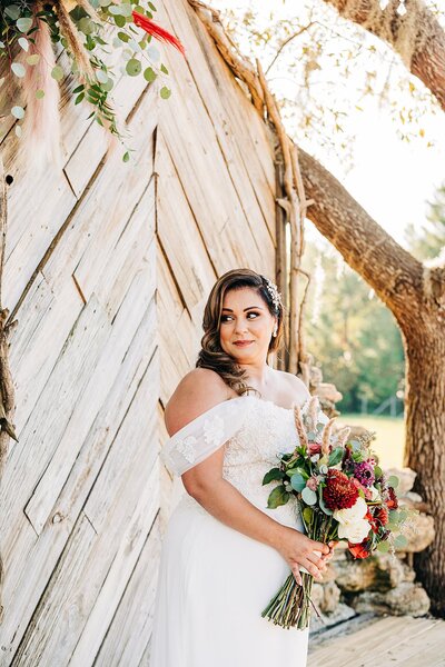 Bride looking over her shoulder, smiling  at the altar with beautiful bouquet