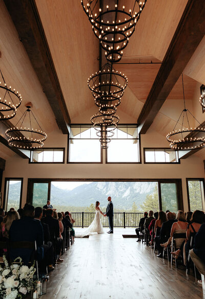 Gorgeous indoor wedding ceremony with a mountain backdrop at Black Canyon Inn the Boulders in Estes Park, Colorado