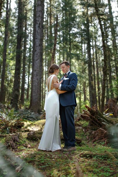 A elopement couple surrounded by ferns, moss and trees in Ecola State Park in Oregon
