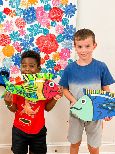 Artcie kids holding up colorful fish they made