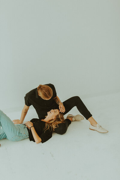 Girl lays in boyfriends lap, looking  at each other while he plays with her hair in calgary photo studio